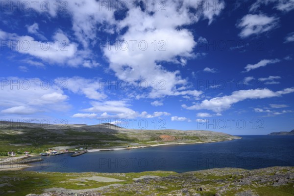 Green meadows on the banks of Syltefjord with clouds in the blue sky, landscape with a lake and