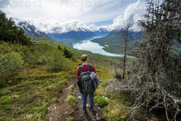 Climbers on a hiking trail, Slaughter Ridge Trail, view of snowy mountains and turquoise lake Kenai