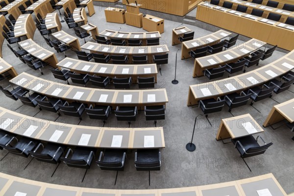 Plenary hall deserted with the seats of deputies and the government bank. Behind it is the coat of
