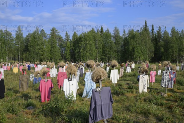 Artwork outdoor installation The silent people of Reijo Kela Straw dolls wear colorful clothes in a