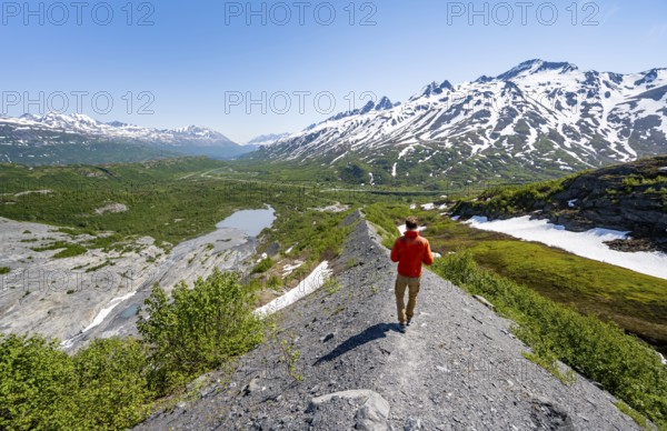 Hikers on glacial moraine, view of the vast Tsina River valley with mountains, Worthington Glacier