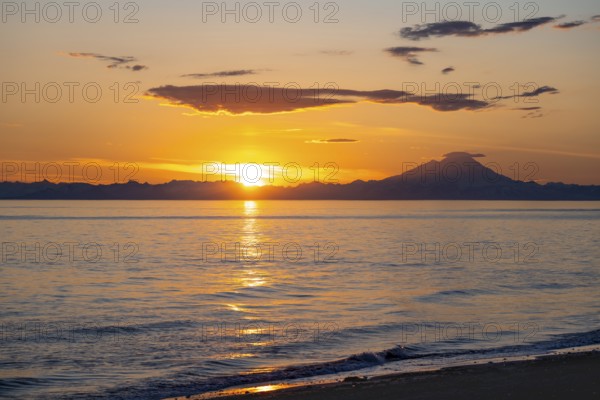 View of Cook Inlet on white mountain peaks of Mount Redoubt at sunset, picturesque golden light of