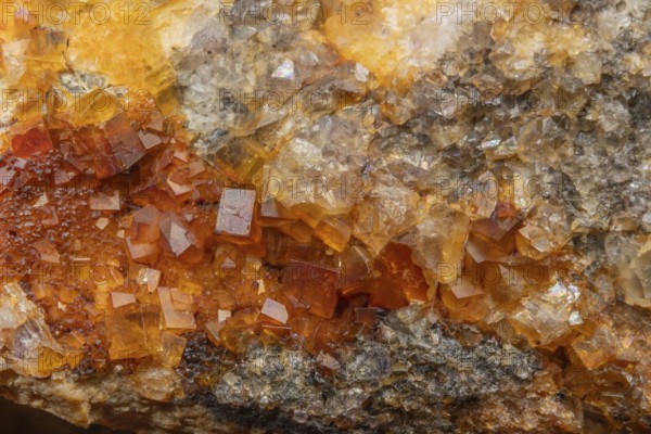 Shiny crystals of blue and orange color can be seen in this mineral formation. They are sparkling