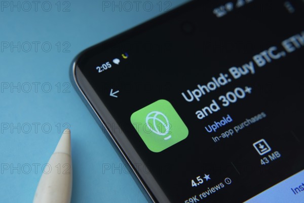 Dhaka, Bangladesh- 19 Sep 2025: On a blue surface, a smartphone displays the Uphold app within the