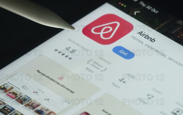 Dhaka, Bangladesh- 21 Nov 2025: Airbnb app on a iPad screen with a pen pointing at the install