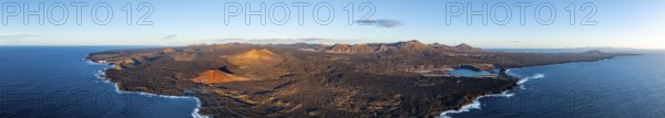 Coast with lava fields, volcanic landscape near Los Hervideros with red volcano Montaña Bermeja, in