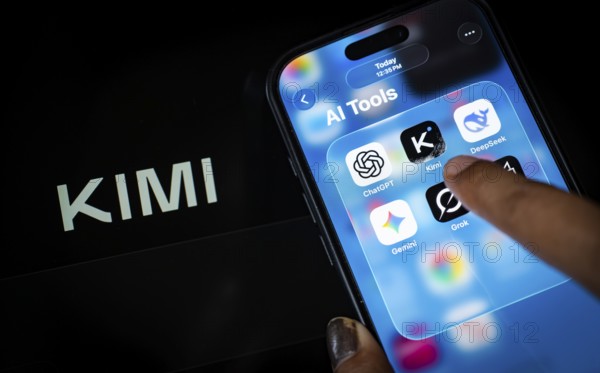 In this photo illustration, a person uses the Kimi AI chatbot on a smartphone while the KIMI logo