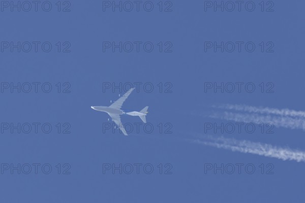 Boeing 747 jumbo jet cargo aircraft flying in a blue sky with contrails or vapour trails behind,