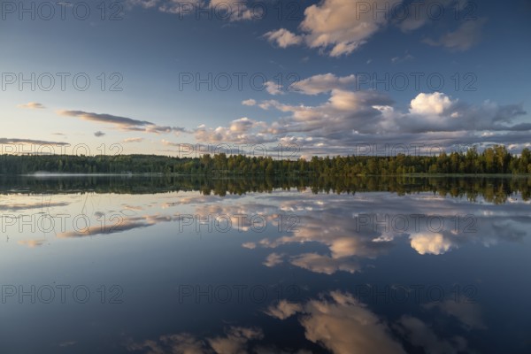 Clouds reflected on the water surface, forest lake, evening mood, at Sunne, Sweden