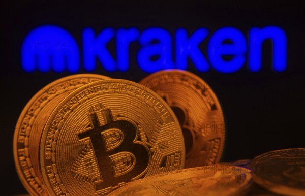 Dhaka, Bangladesh- 01 Nov 2025: Close-up of Bitcoin coins with the Kraken logo visible on a screen
