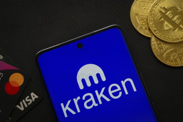 Dhaka, Bangladesh- 26 Aug 2025: Smartphone displaying Kraken logo surrounded by Bitcoin coins and