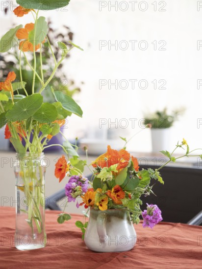 Florist arranging nasturtiums and verbenas in a ceramic jug during an ikebana workshop