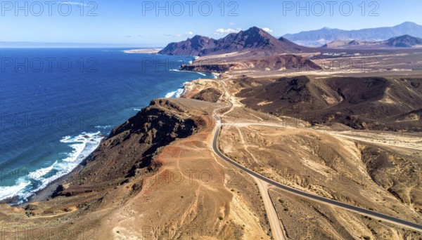Desert landscape converges with ocean along a rugged coastal area, shore break at cliffs, blue