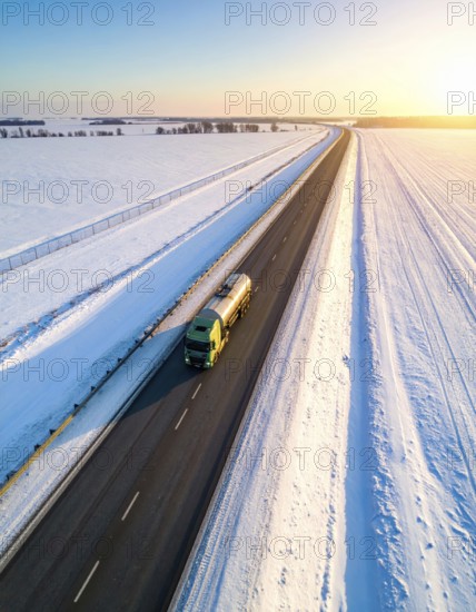 Petrol cargo truck lorry tanker driving on highway hauling oil products at sunrise, wide snowy