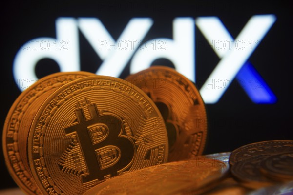 Dhaka, Bangladesh- 03 Oct 2025: Close-up of Bitcoin coins with the Dydx logo visible on a screen in