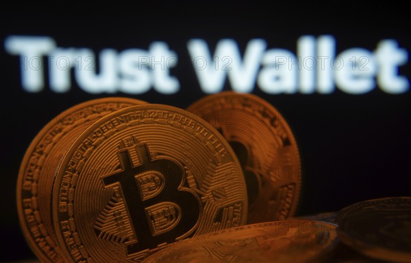 Dhaka, Bangladesh- 30 Sep 2025: Close-up of Bitcoin coins with the Trust Wallet logo visible on a