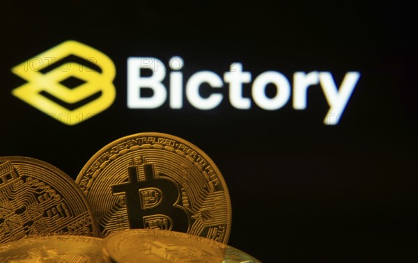 Dhaka, Bangladesh- 09 Sep 2025: Close-up of Bitcoin coins with the Bictory logo visible on a screen