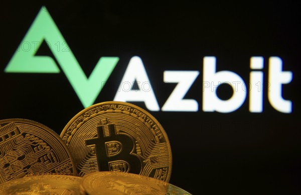 Dhaka, Bangladesh- 02 June 2025: Close-up of Bitcoin coins with the Azbit logo visible on a screen