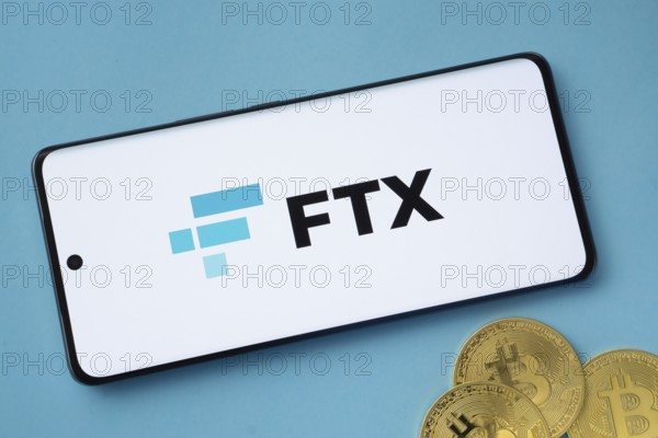Dhaka, Bangladesh- 26 Aug 2025: FTX logo on smartphone screen near Bitcoin coin and QR code on blue