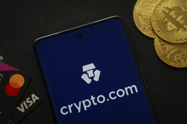 Dhaka, Bangladesh- 26 Aug 2025: Smartphone displaying Crypto.com logo surrounded by Bitcoin coins