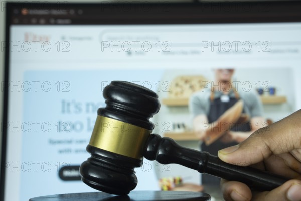 Dhaka, Bangladesh- 20 June 2025: A hand holds a gavel in front of a computer screen displaying