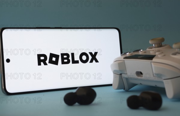 Dhaka, Bangladesh- 26 July 2025: A smartphone with a Roblox icon next to a controller and earbuds