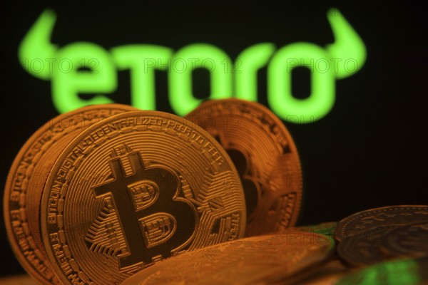 Dhaka, Bangladesh- 27 March 2025: Close-up of Bitcoin coins with the eToro logo visible on a screen