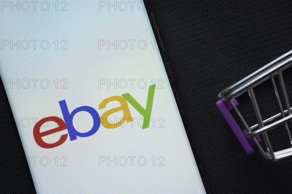 Dhaka, Bangladesh- 03 July 2025: A smartphone displaying the eBay logo next to a miniature shopping