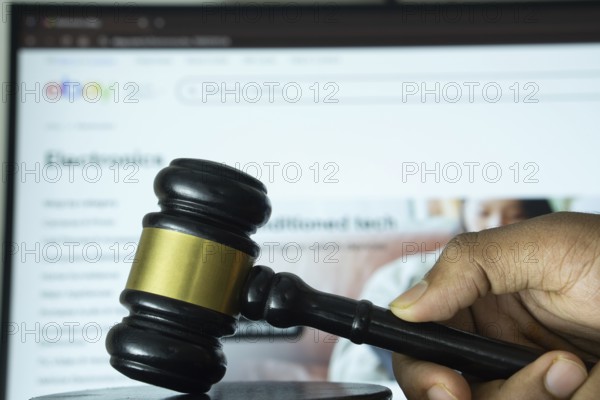Dhaka, Bangladesh- 20 June 2025: A hand holds a gavel in front of a computer screen displaying