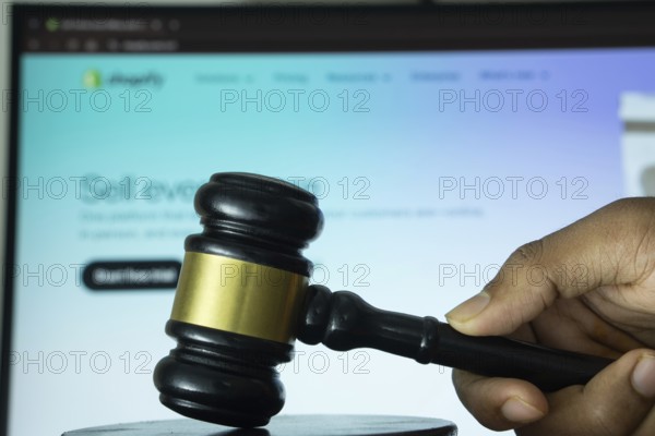 Dhaka, Bangladesh- 20 June 2025: A hand holds a gavel in front of a computer screen displaying