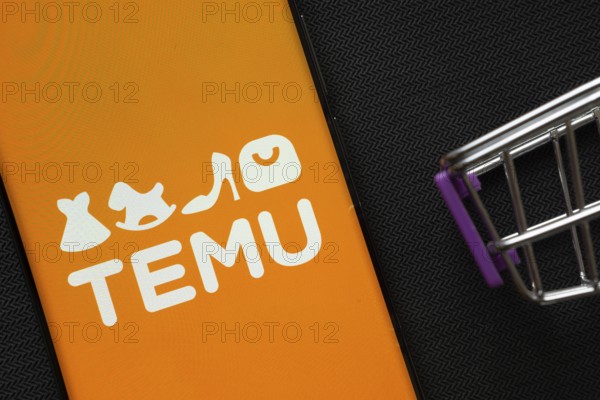Dhaka, Bangladesh- 03 July 2025: A smartphone displaying the Temu logo next to a miniature shopping