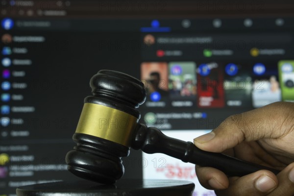 Dhaka, Bangladesh- 20 June 2025: A hand holds a gavel in front of a computer screen displaying