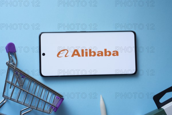 Dhaka, Bangladesh- 03 July 2025: Smartphone displaying Alibaba logo with shopping cart on a blue