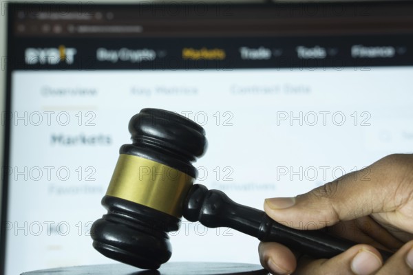Dhaka, Bangladesh- 20 June 2025: A hand holds a gavel in front of a computer screen displaying