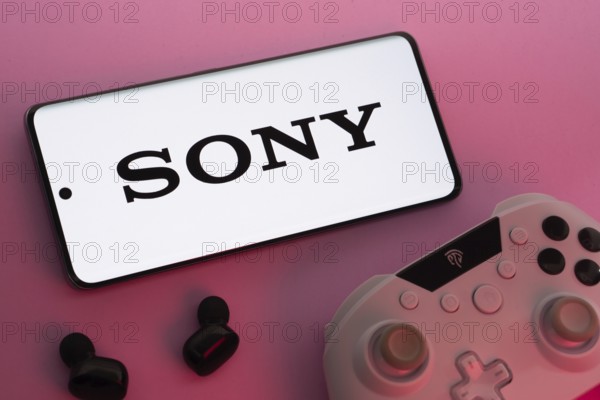 Dhaka, Bangladesh- 02 July 2025: Smartphone with sony logo, game controller, and earbuds on a pink