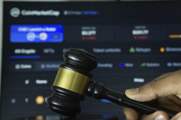 Dhaka, Bangladesh- 20 June 2025: A hand holds a gavel in front of a computer screen displaying
