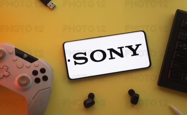 Dhaka, Bangladesh- 03 June 2025: Smartphone with Sony logo, game controller, and earbuds on a