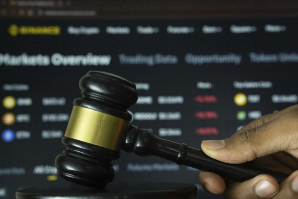 Dhaka, Bangladesh- 20 June 2025: A hand holds a gavel in front of a computer screen displaying