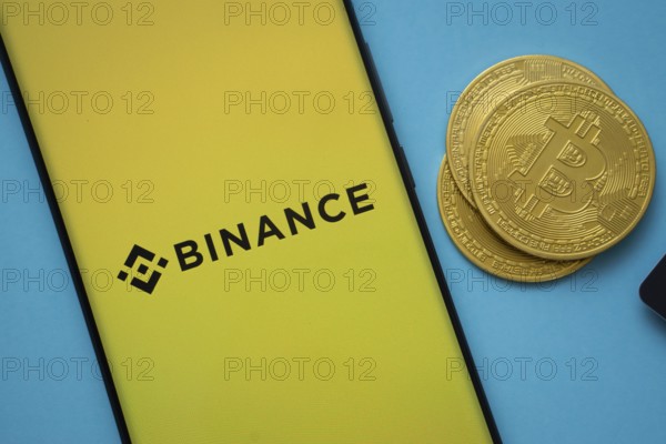 Dhaka, Bangladesh- 22 June 2025: Binance logo on smartphone screen near Bitcoin coin and QR code on