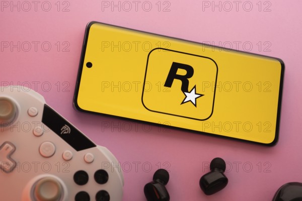 Dhaka, Bangladesh- 17 June 2025: Smartphone with rockstar games logo, game controller, and earbuds