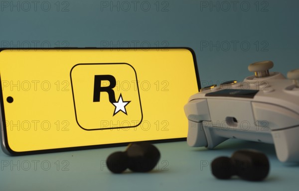 Dhaka, Bangladesh- 17 June 2025: A smartphone with a rockstar games app icon next to a controller