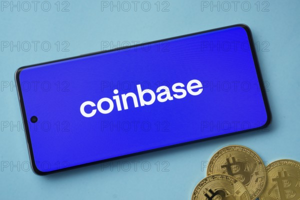 Dhaka, Bangladesh- 17 June 2025: Smartphone displaying Coinbase logo with Bitcoin coins on a blue