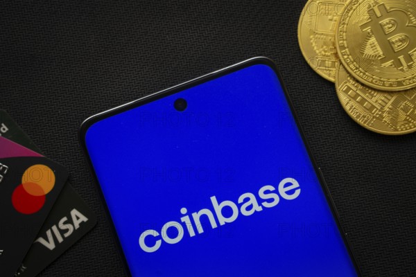 Dhaka, Bangladesh- 17 June 2025: Smartphone displaying Coinbase logo surrounded by Bitcoin coins