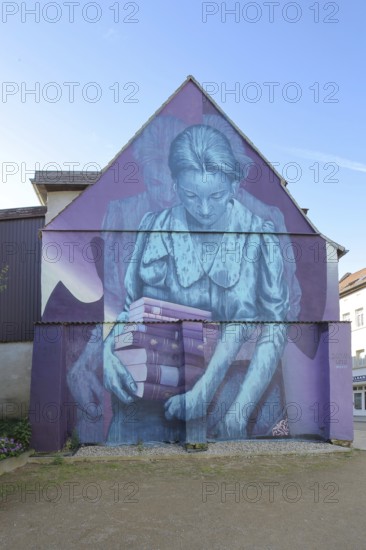 Mural Knowledge by Sokar Uno 2023, blue violet house wall, woman carrying a stack of books, books,