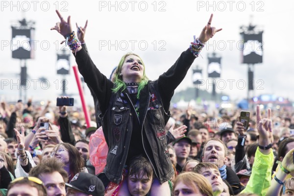 Festival visitor on shoulders with a French fries fork shaped like a hand at the Rock am Ring