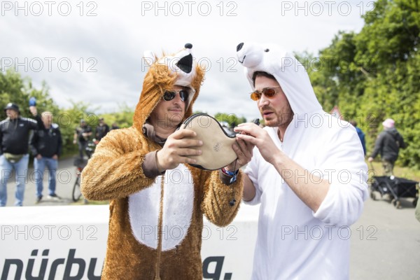 Two festival visitors in animal costumes drink from a horn at the Rock am Ring festival on Friday,