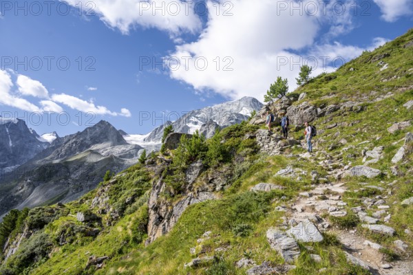 Three mountaineers on a hiking trail, mountain landscape near Arolla, behind mountain peak Mont