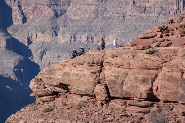 Visitors climb on rock formation rising above the canyon at Guano Point in Grand Canyon West near