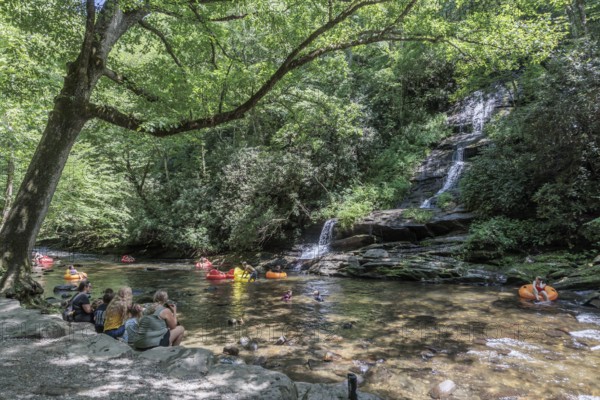 Visitors swimming and floating on inflatables at the base of Tom Branch Falls along Deep Creek in