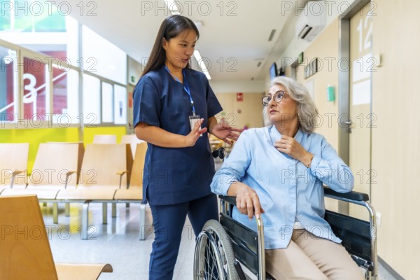 Young nurse assisting and engaging in conversation with senior woman in wheelchair, providing
